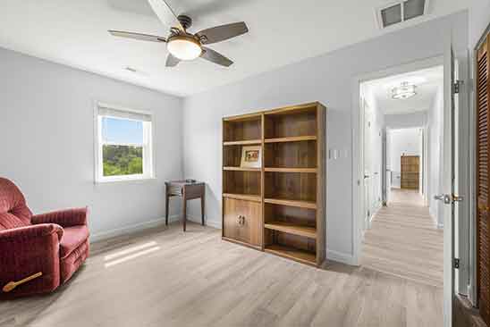 Bright upstairs room at 1701 Harrington Road, Orange VA, featuring wood floors, ceiling fan, window view, and hallway access.