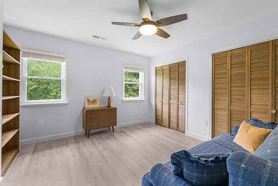 Spacious bedroom at 1701 Harrington Road, Orange VA, with ceiling fan, wood flooring, two closets with louvered doors, and large windows.