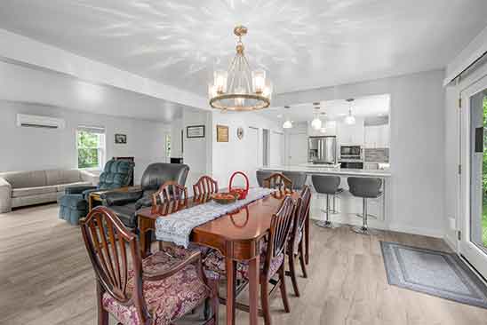 Dining area and kitchen at 1701 Harrington Road, Orange VA, featuring elegant chandelier, wood-style floors, breakfast bar with stools, and open-concept layout.