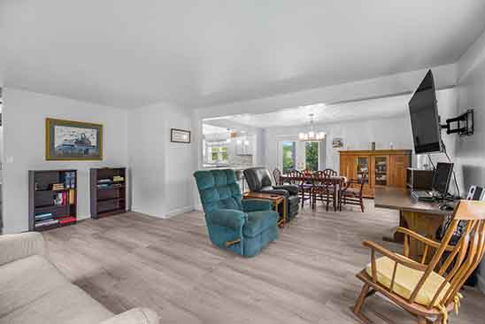 Interior view of open living and dining room at 1701 Harrington Road, Orange VA, featuring wood-style flooring, ample seating, natural light, and adjacent kitchen access.
