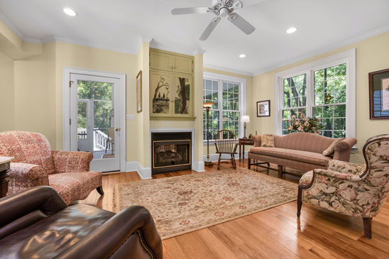 BFamily room at 3665 Old River Trail in Powhatan, Virginia, featuring large windows, a gas fireplace, and traditional furnishings. This inviting space is part of the 2001 addition to Pleasant Oak, offering comfort, natural light, and views of the surrounding gardens.