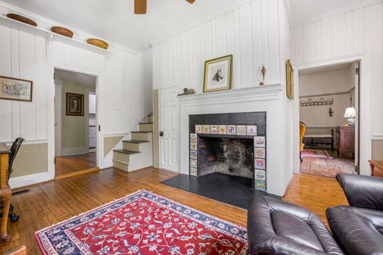 Interior view of 3665 Old River Trail in Powhatan, Virginia, featuring original heart pine floors, wide board paneling, and a tiled fireplace.
