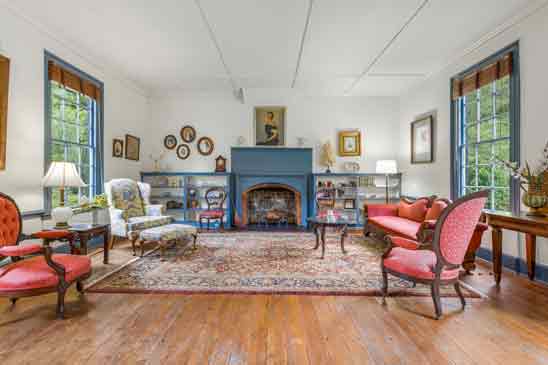 Elegant parlor at 3665 Old River Trail in Powhatan, VA—featuring original heart pine floors, deep-set six-over-nine windows, and a striking colonial fireplace with built-in bookcases. 
