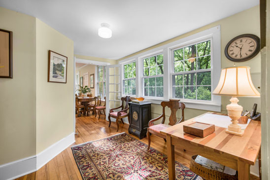 Bright passageway at 3665 Old River Trail in Powhatan, Virginia, connecting the original home to the 2001 renovation. Lined with windows overlooking the wooded grounds, this inviting space blends old and new, offering natural light, warm wood floors, and a seamless transition into the modern kitchen and family room at Pleasant Oak.