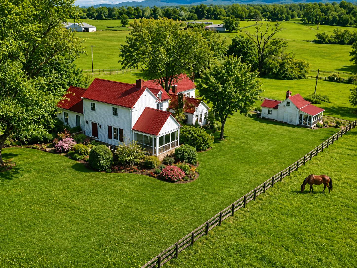 Working farm with red-roofed farmhouse, fenced pasture, grazing horse, and green countryside landscape