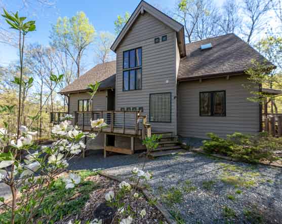 Secluded retreat property in Nelson County, VA, featuring a contemporary wood-sided home with large windows, a wraparound deck, and a tranquil wooded setting, perfect for relaxation and nature escapes.
